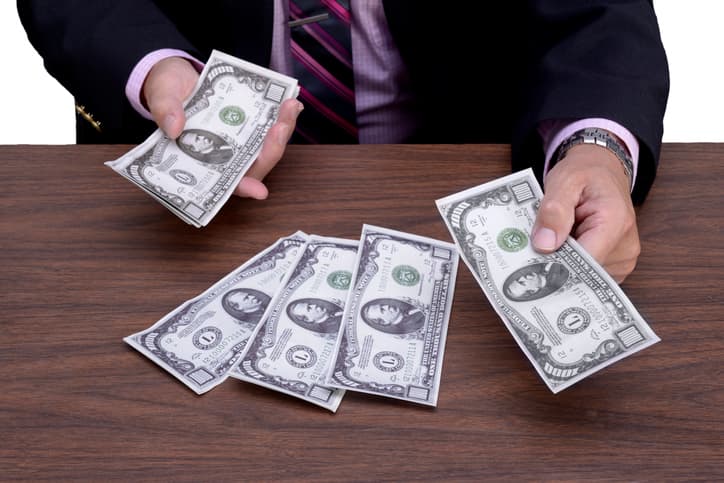Business man counting out $1000 bills on his desk