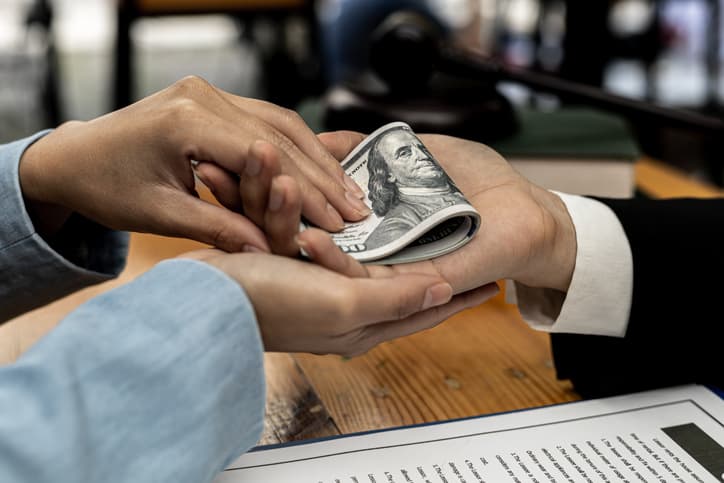Second hand images of people putting dollars in their hands, they are business partners who are doing fraudulent behavior to benefit from joint projects. Business fraud and bribery is illegal concept.