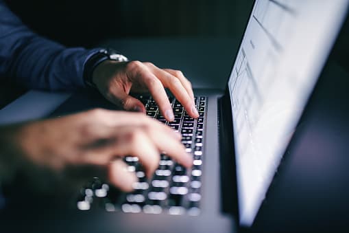 Close up of hands typing on laptop. Night work concept, private equity, survey, ernst & young
