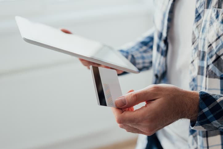 Man using tablet while holding credit card