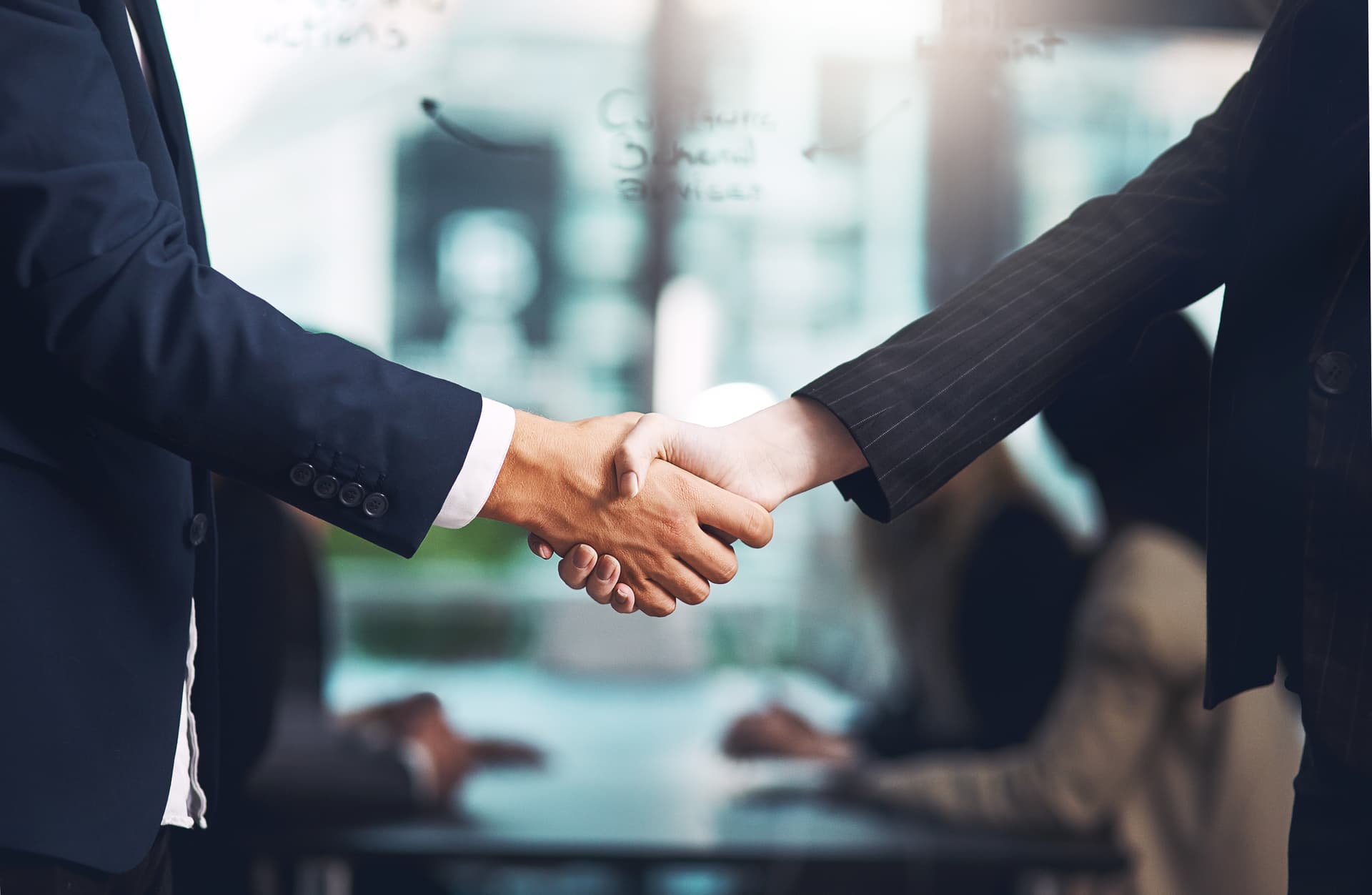 Two men in suits shake hands - only their arms are visible