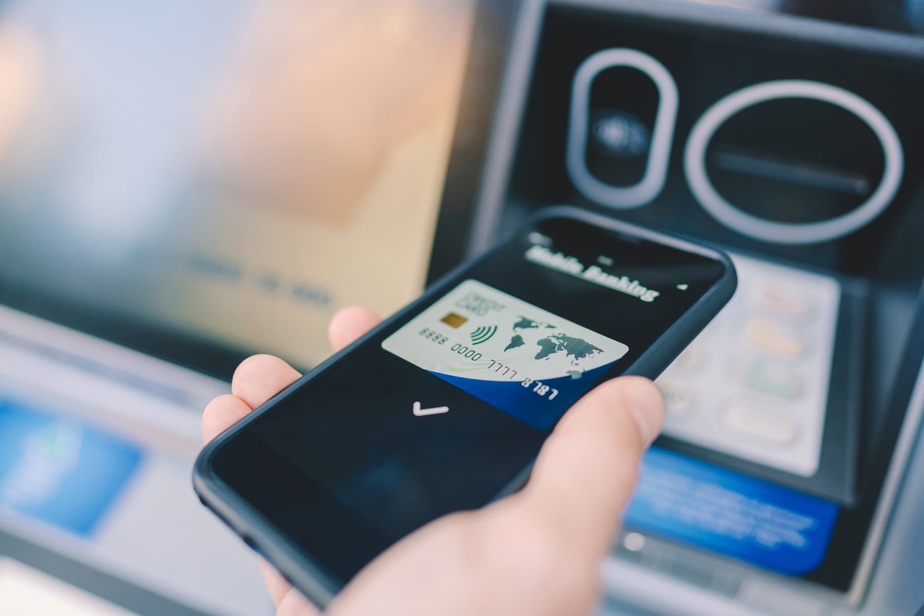 Man at the ATM withdrawing money with smartphone
