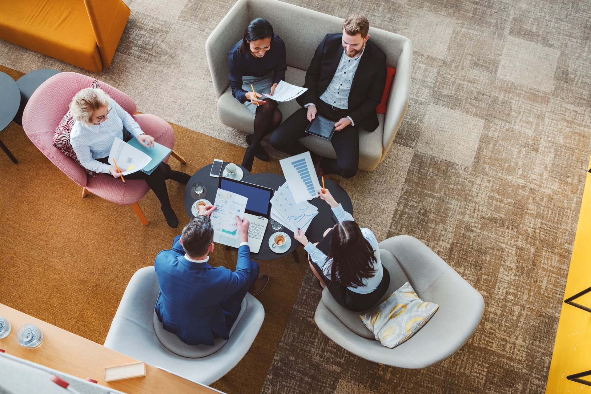 overhead shot of diverse group of people business people working on spreadsheets and charts in a lounge setting