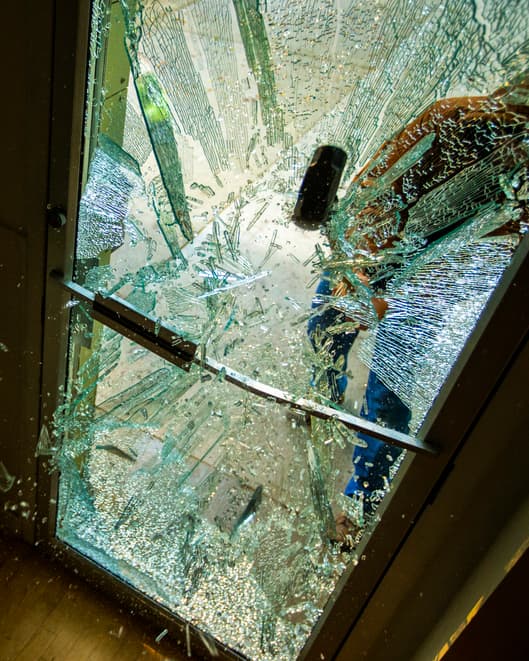 A robber using a sledgehammer to break the glass of a retail store.