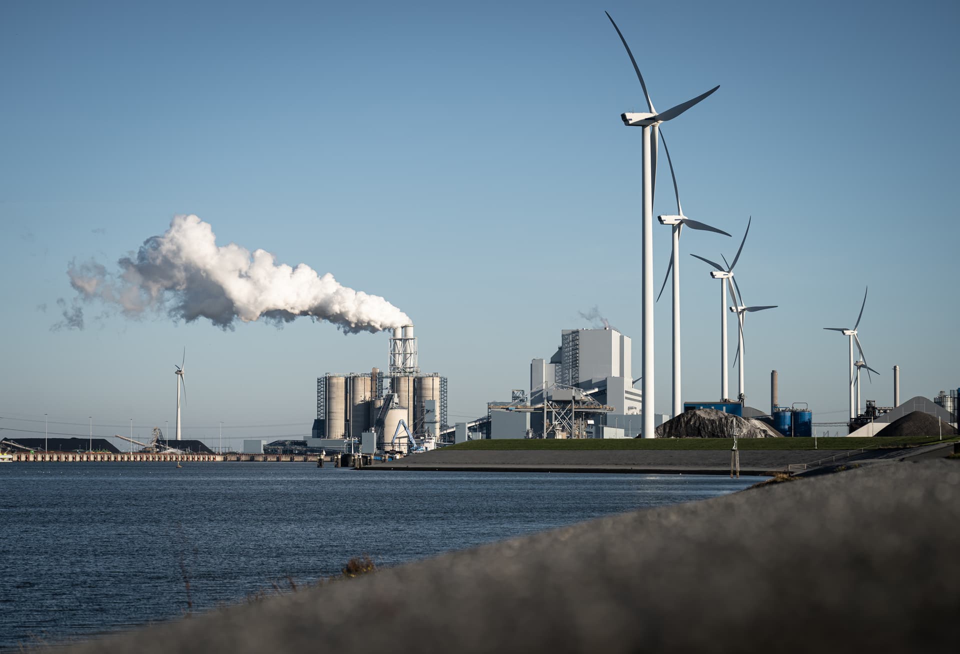 Fossil fuel (coal) power station and wind turbines in the Eemshaven generating power. Energy transition concept.
