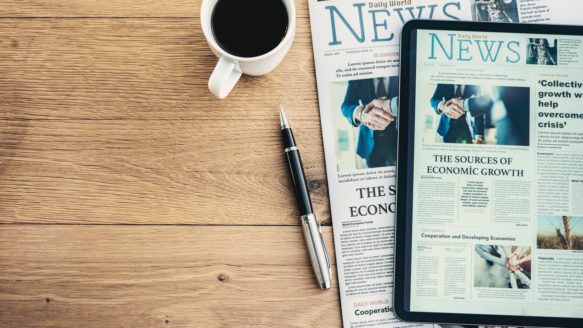coffee cup and pen next to newspaper and tablet with news website