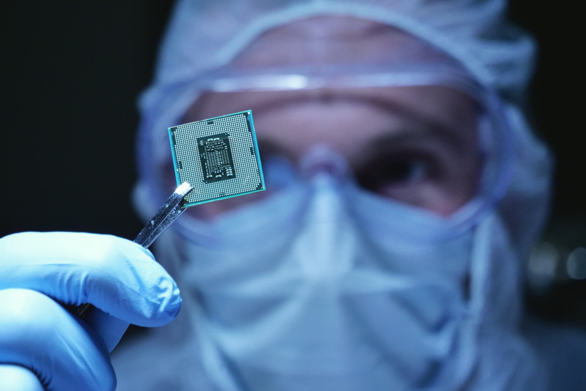 Design engineer in sterile coverall holds microchip