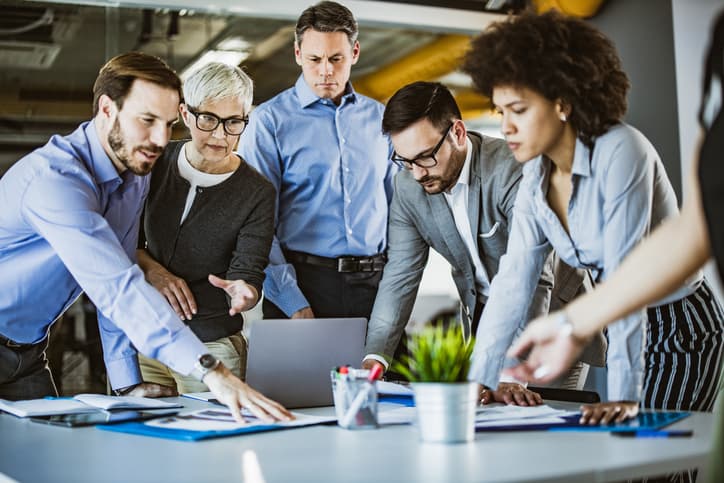 Group of business people cooperating while examining paperwork on a meeting in the office.