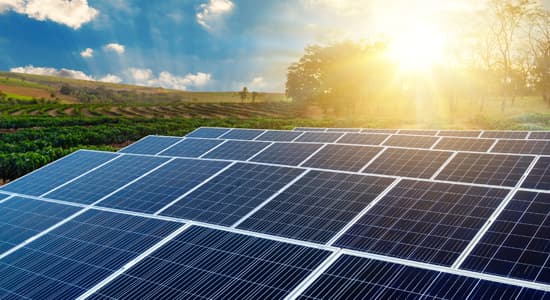 solar panels on a field with the sun in the background
