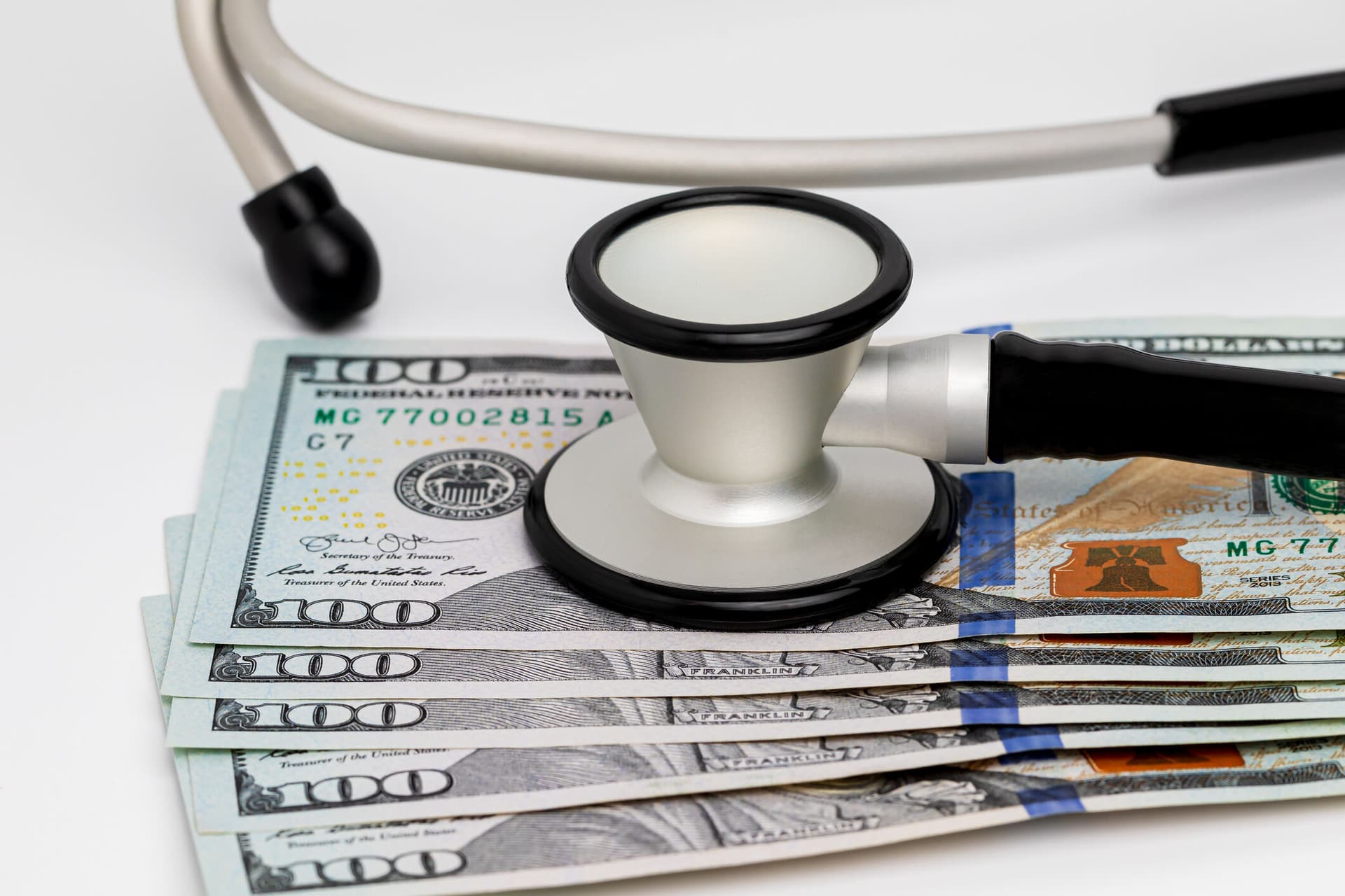 Photo of a stethoscope and cash money, representing concepts of the healthcare, health insurance and medical bills.