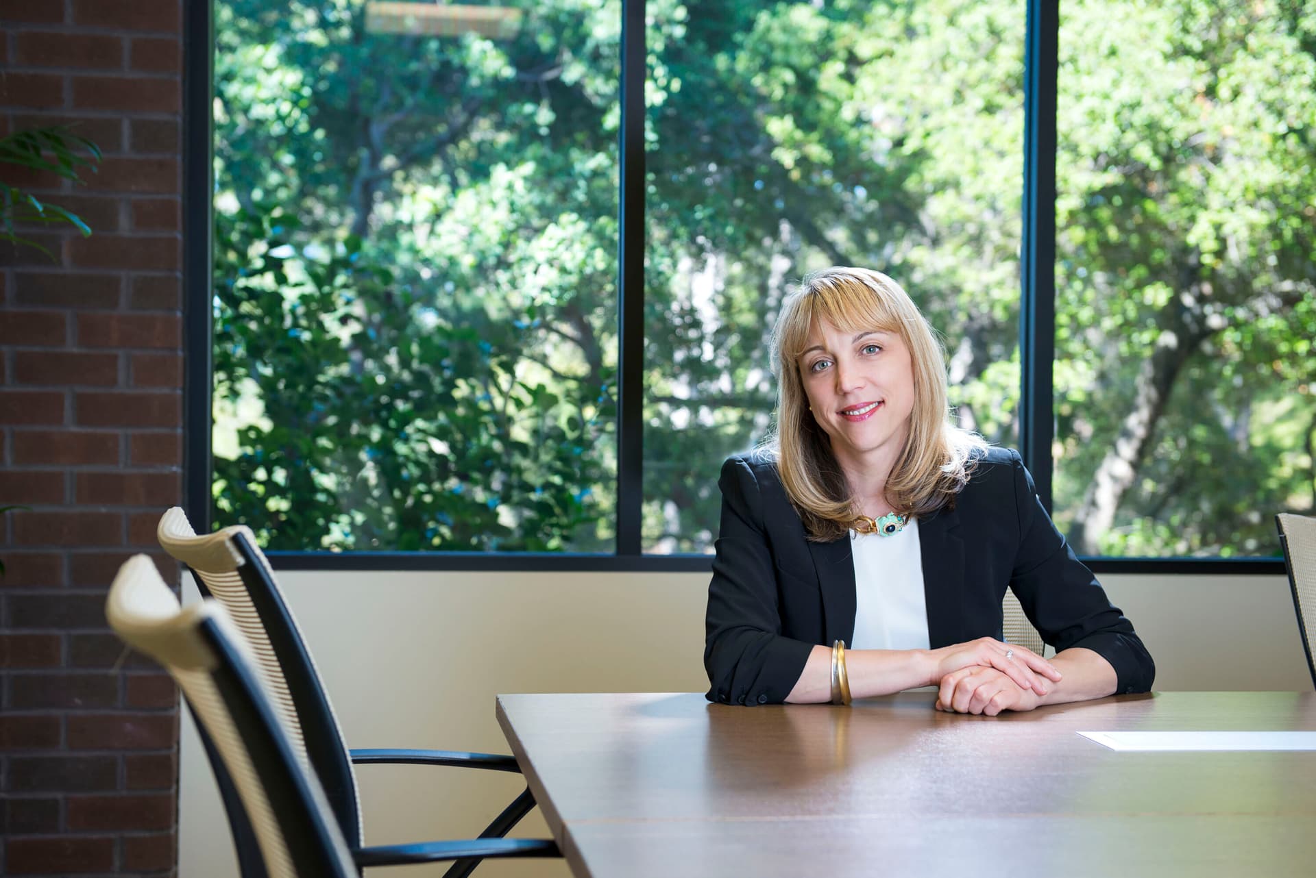 Andrea Auerback sitting at a desk, trees in background