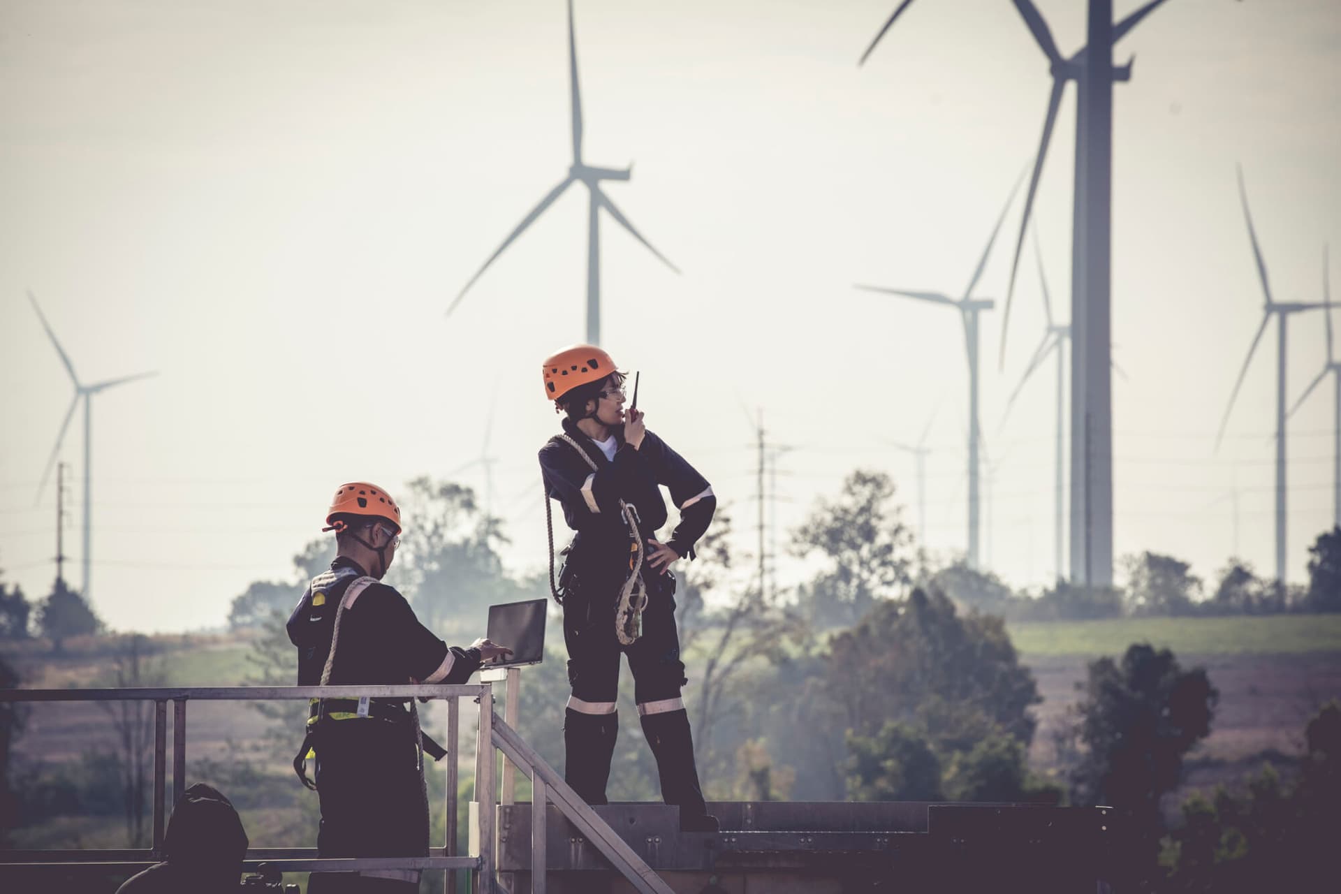 Close up professional wind turbine maintenance team wearing PPE and Safety harness walk working in Wind turbine farm, Green and Renewable Energy concept