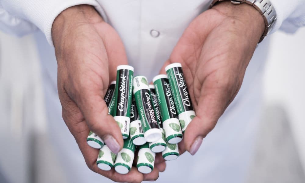 Hands holding a collection of lip balm brand ChapStick