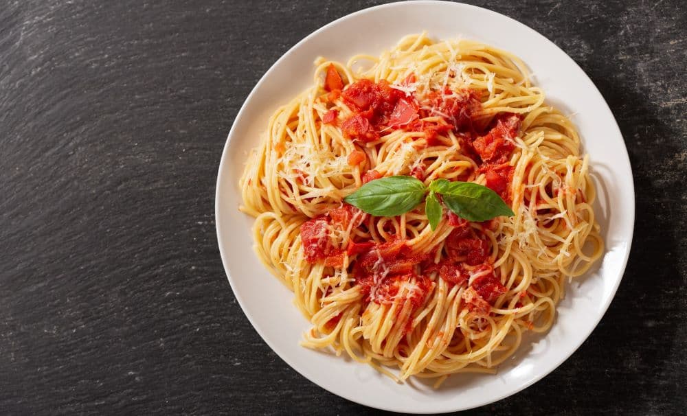 Spaghetti with pasta sauce plated on a dark table.