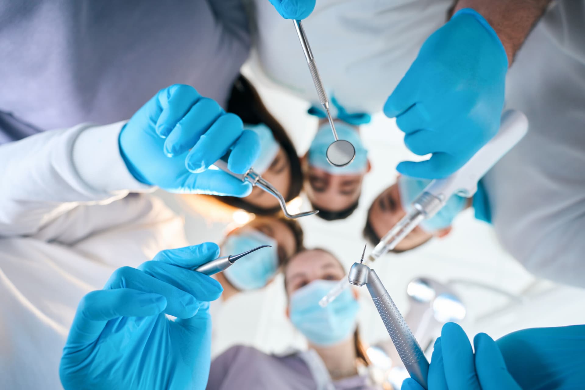 Five dentists with special tools in their hands, people in medical uniforms and protective gloves