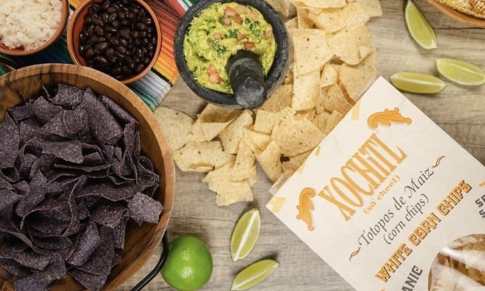 A bag of Xochitl chips with guacamole, lime, beans and black corn chips.