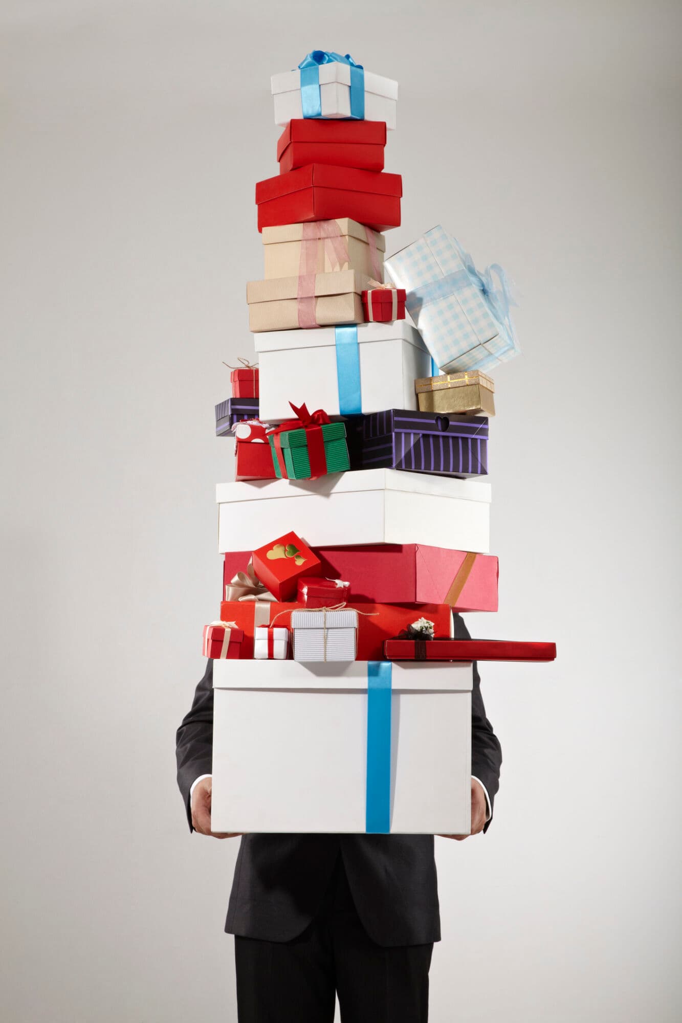 Businessman carrying stack of christmas presents, studio shot.