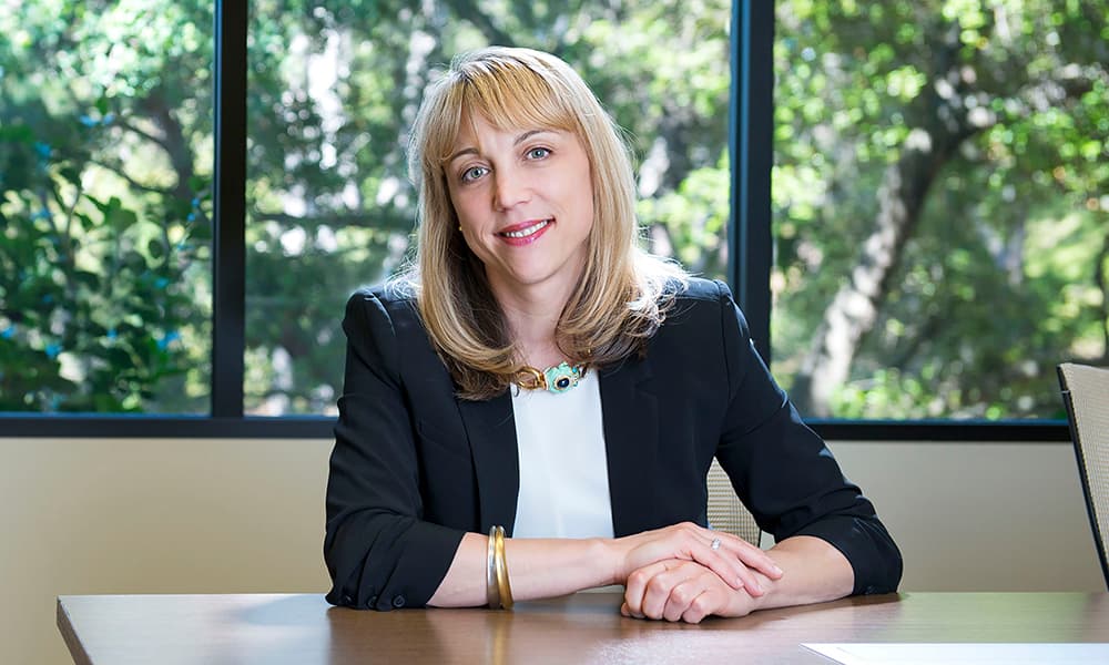 Andrea Auerbach of Cambridge Associates sitting at a table with trees in background