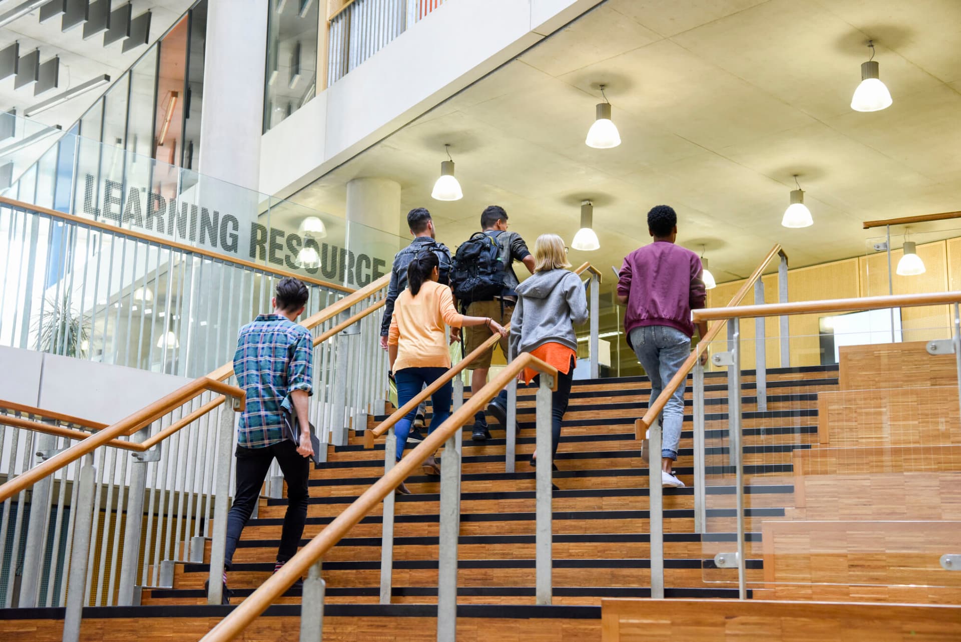 Male and female college students in casual clothing, on way to class, ascending staircase