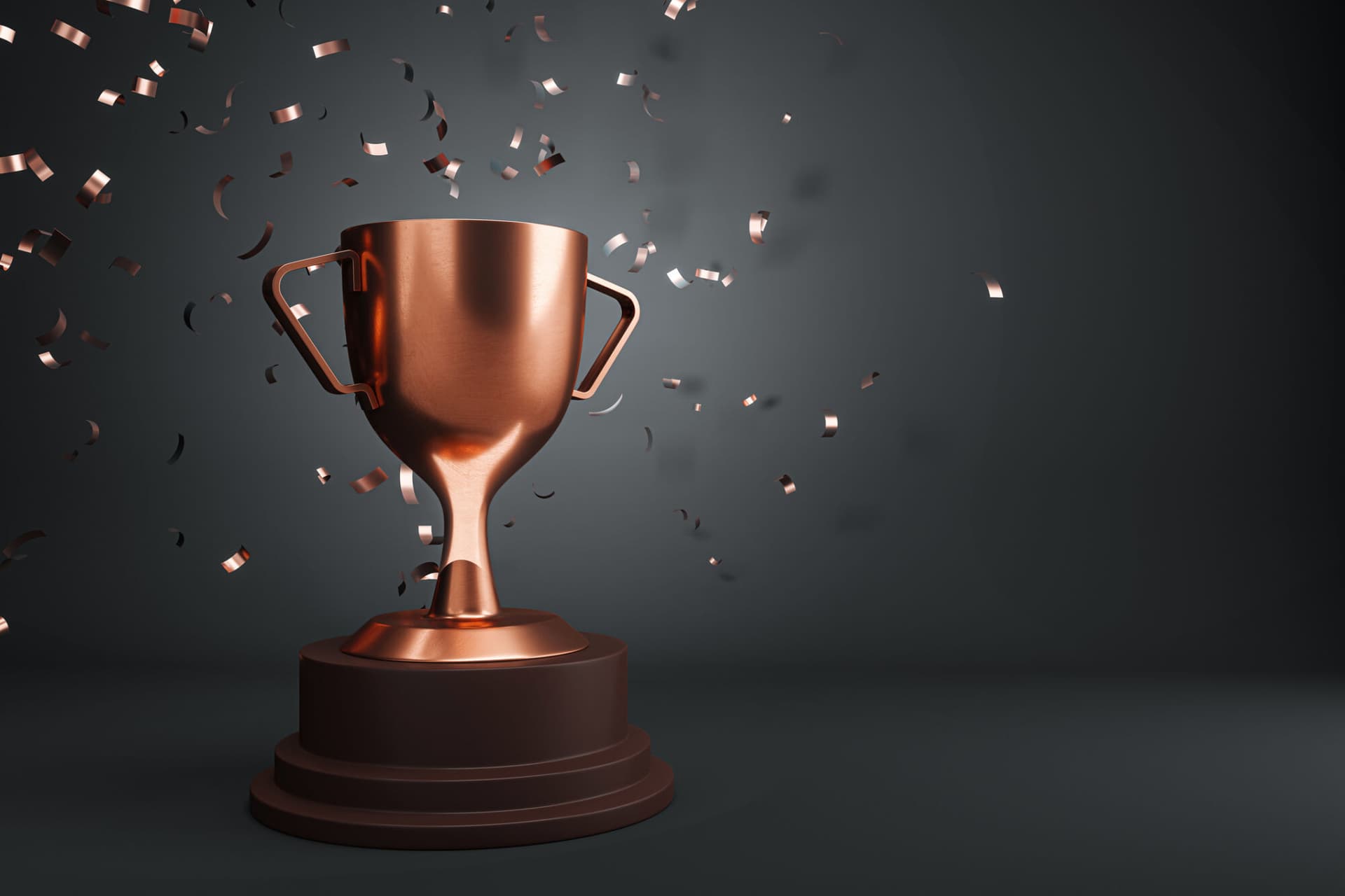 A bronze trophy cup with confetti on a dark background