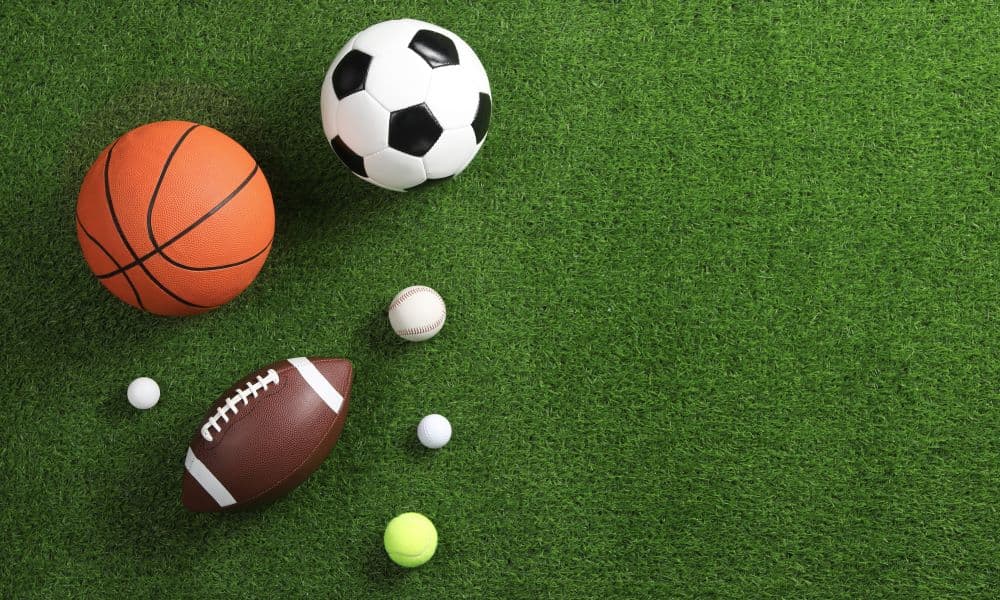 Several sports balls on a grass field.