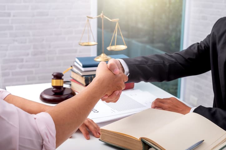 Businessman shaking hands to seal a deal with his partner lawyers or attorneys discussing a contract agreement.