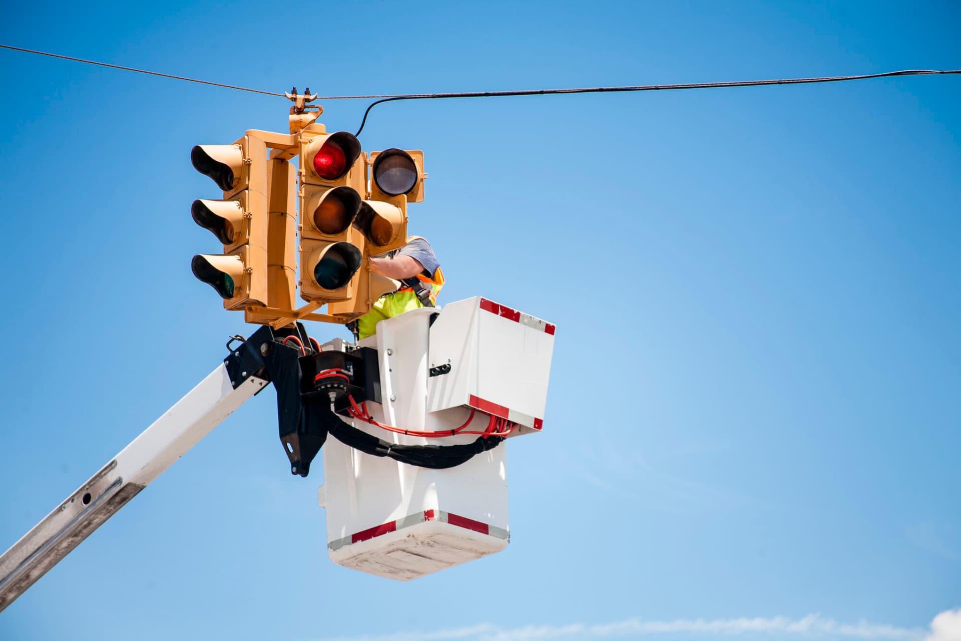 Photo of a utilities worker repairs traffic light in bucket truck.