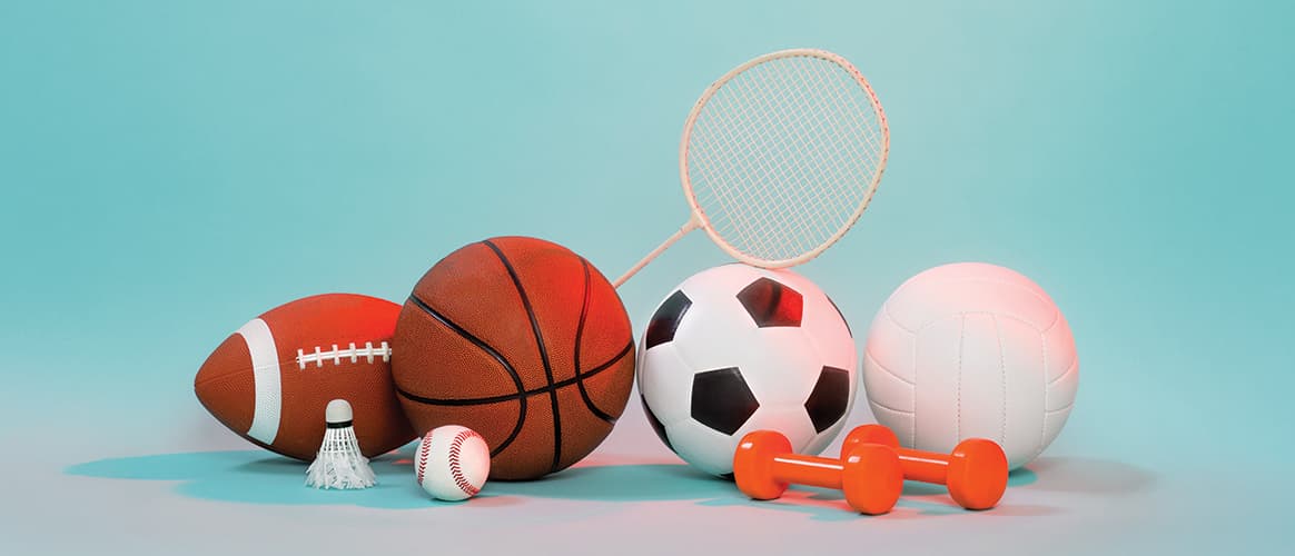 A pile of various sports equipment including a basketball, a shuttlecock and some weights
