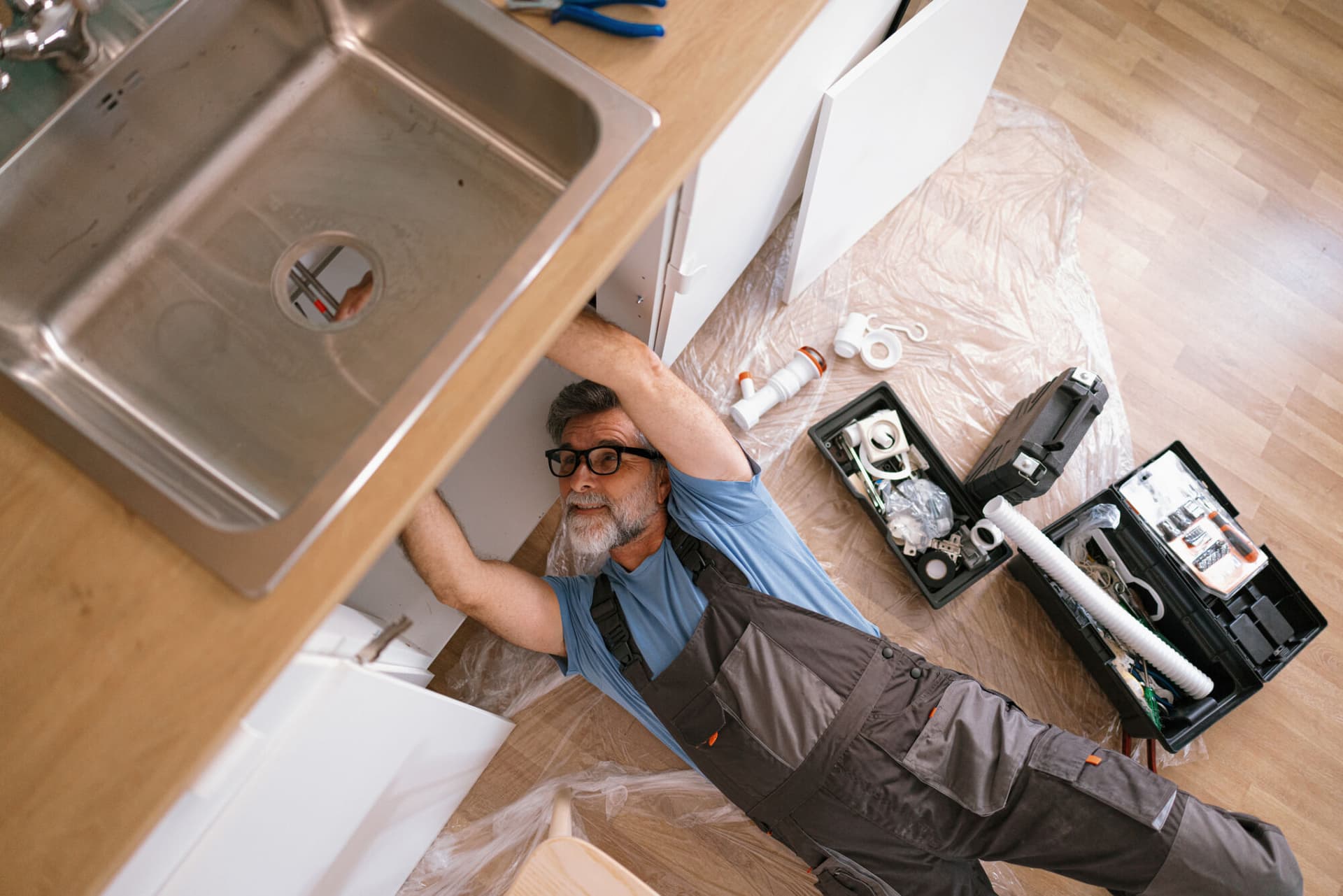 plumber fixing the sink in the kitchen Getty
