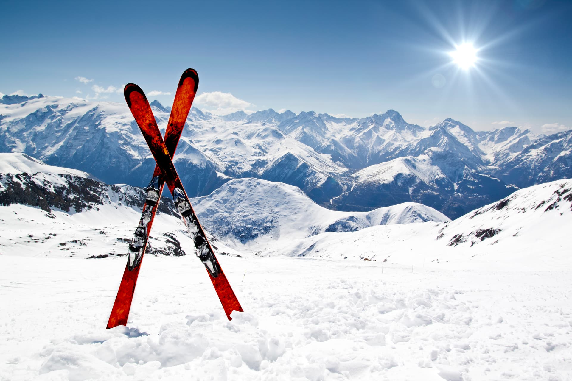 Pair of red skis crossed and wedged in snow on mountain