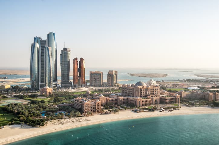 Aerial view of skyscrapers in Corniche bay in Abu Dhabi, UAE. Turquoise water in the front and blue sky in the distance combined with building exterior in the middle.