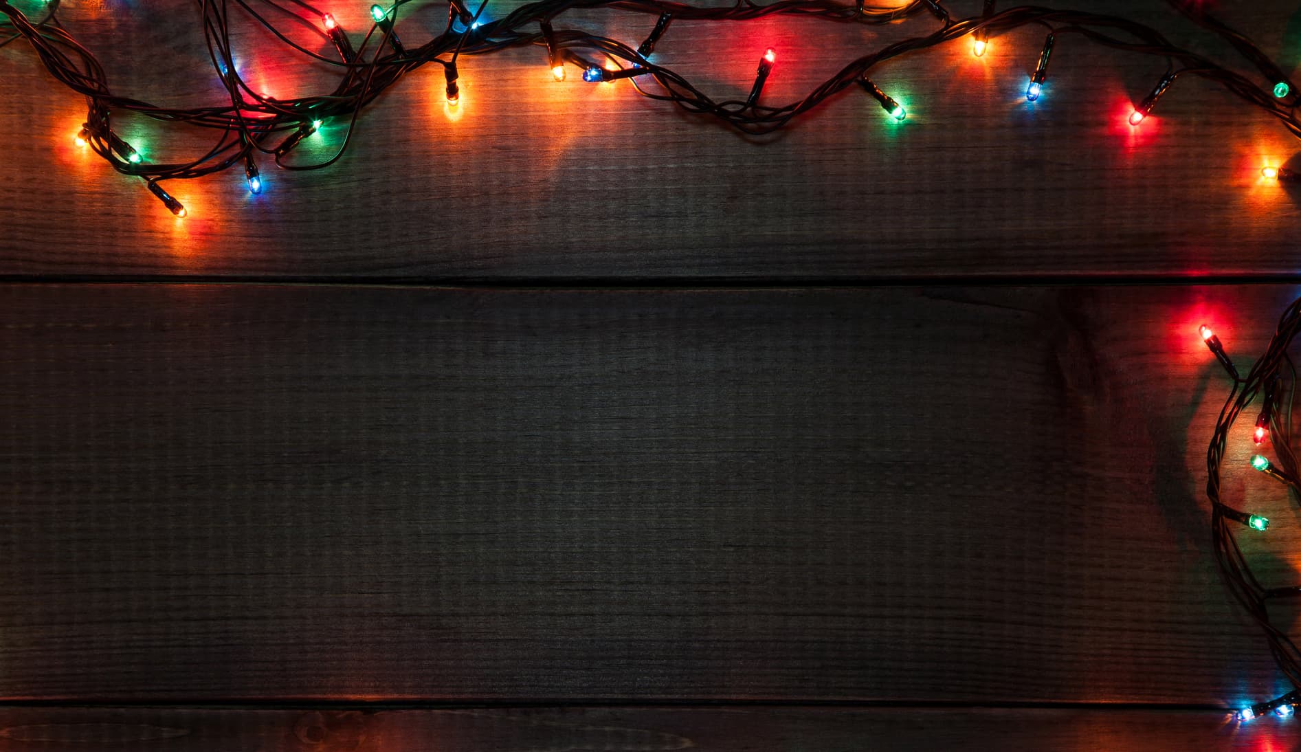 Coloured festive lights against a wooden background