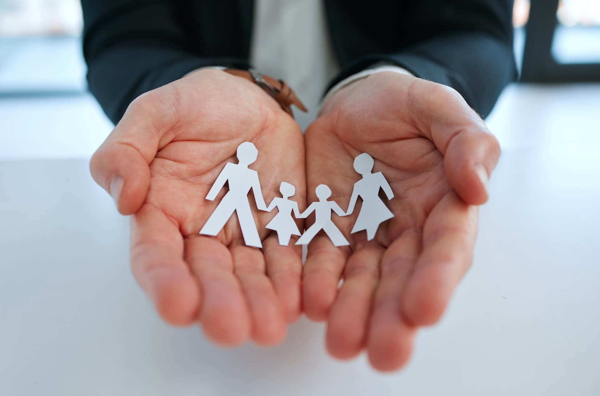 A businessman holds a paper cut-out of a family in his hands