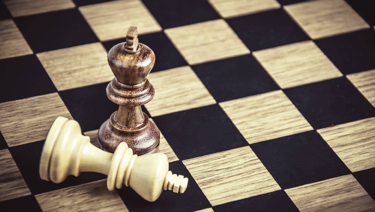Chess board kings on a board, with the white piece knocked over