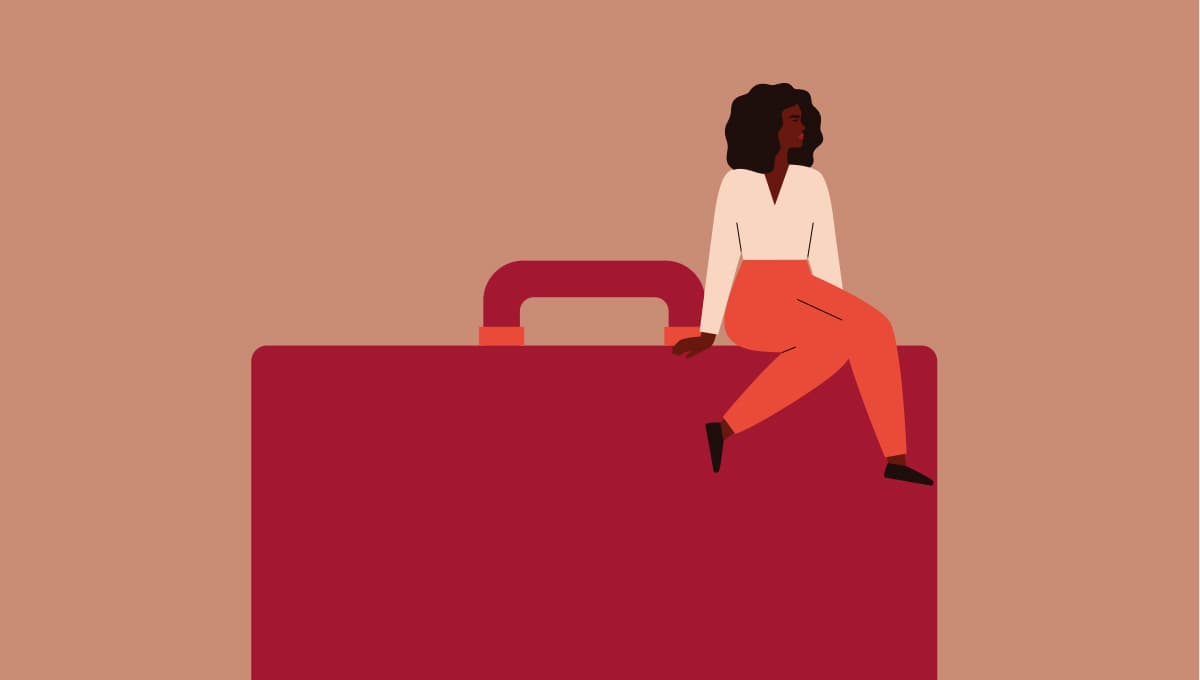 A woman sits upon a suitcase