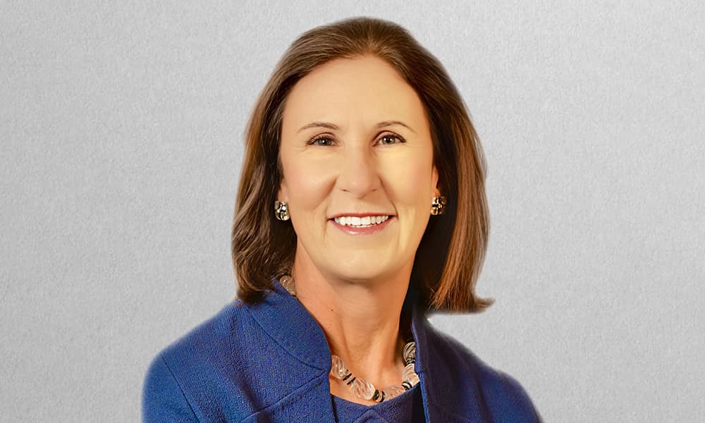 Headshot of Beatrice Mitchell in a blue blouse with a gray background
