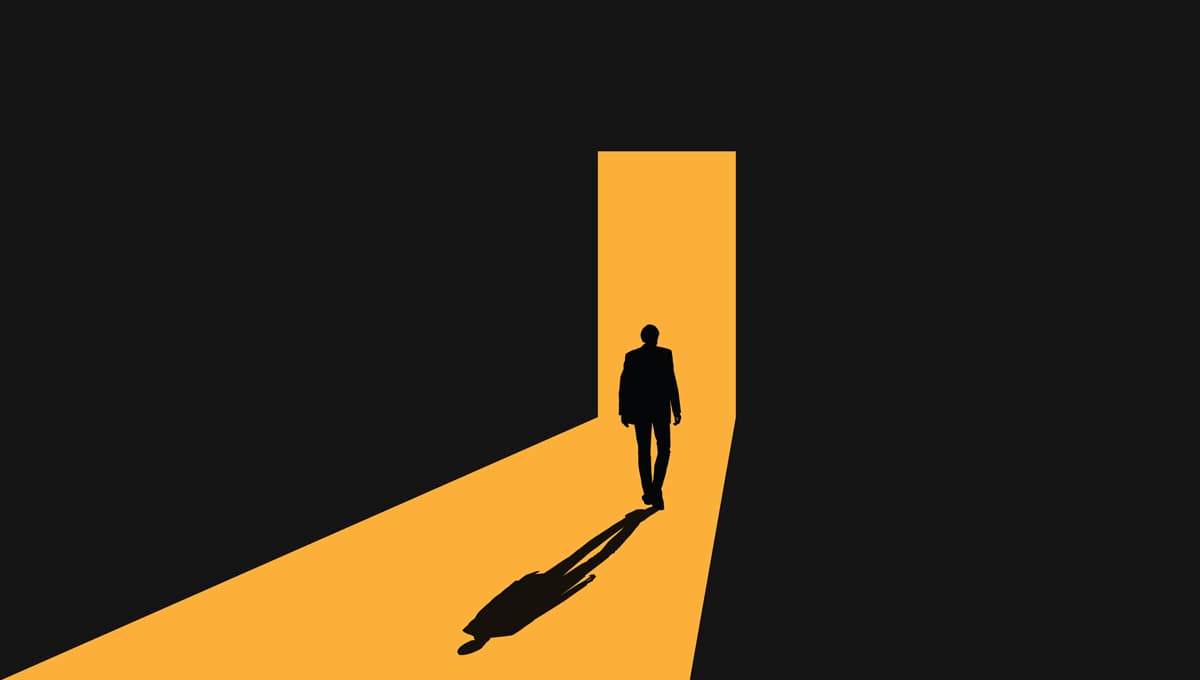 A shadowy figure approaches the light of a doorway