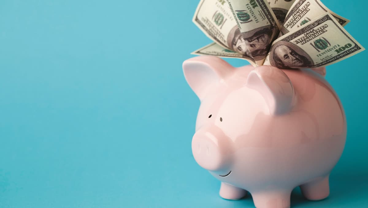 A pink piggy bank stuffed with dollar bills