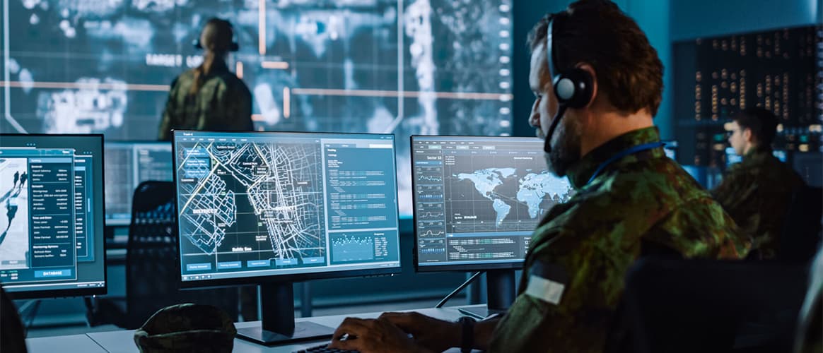 A military command and communications centre with operatives looking at urban maps on computer screens