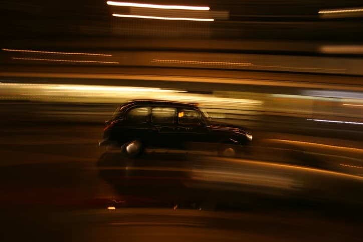Night shot of a London Black Cab on motion blur background.