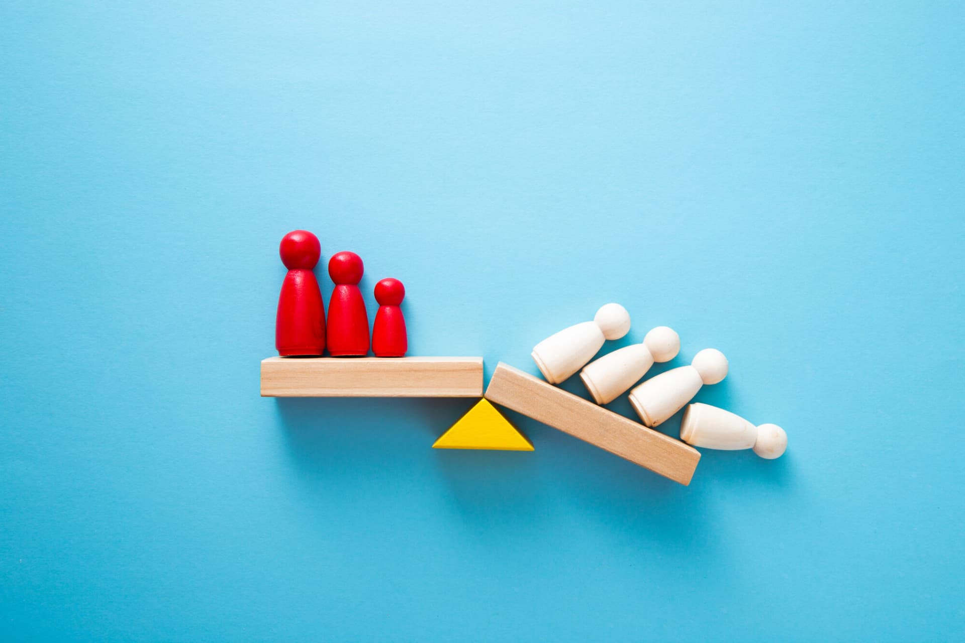 Wooden figures on a shelf, half of whom are falling off