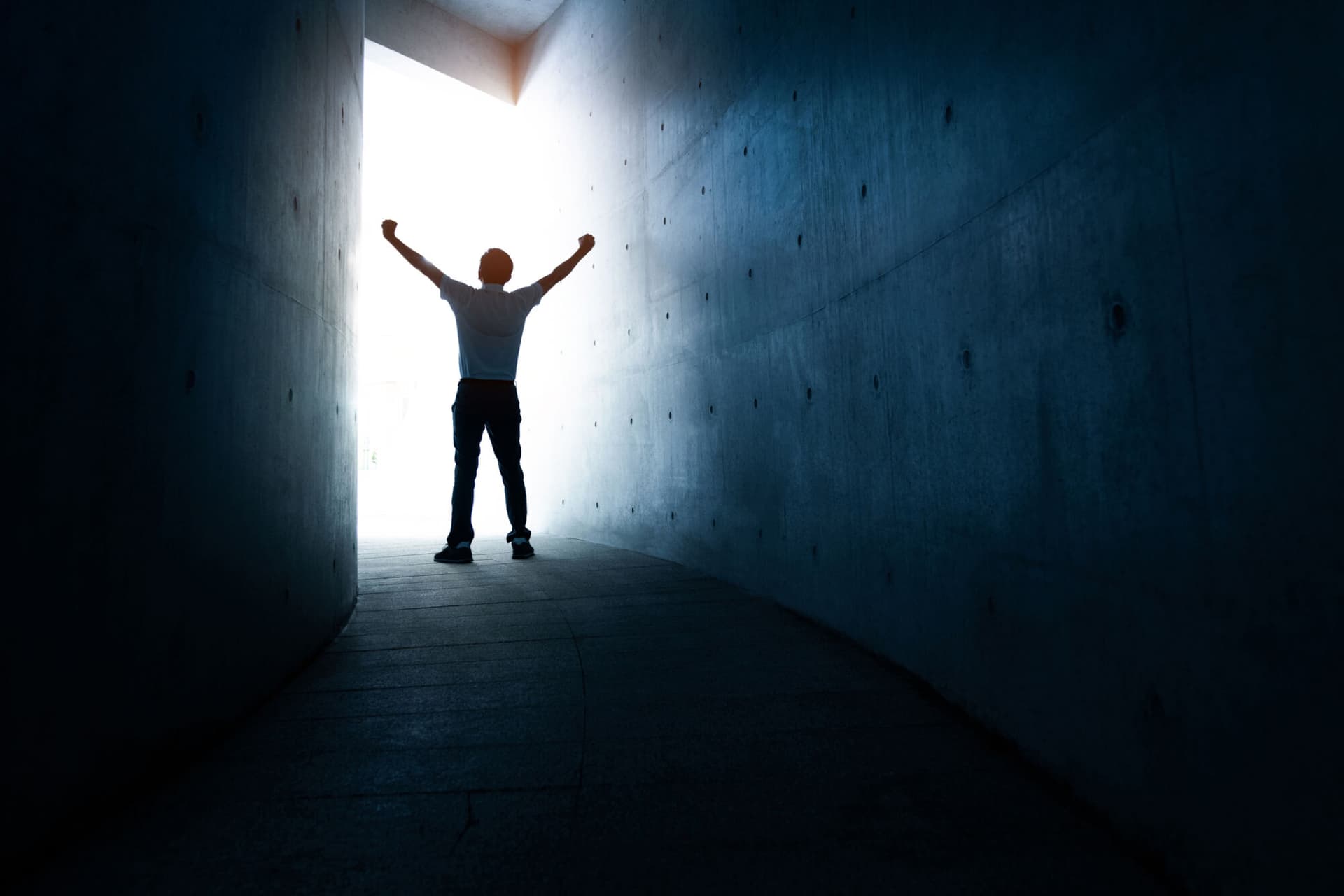 A man standing in the light at the end of a dark tunnel