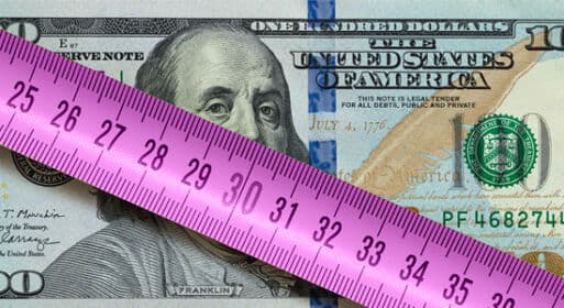 A ten dollar US bill with a ruler on top of it.