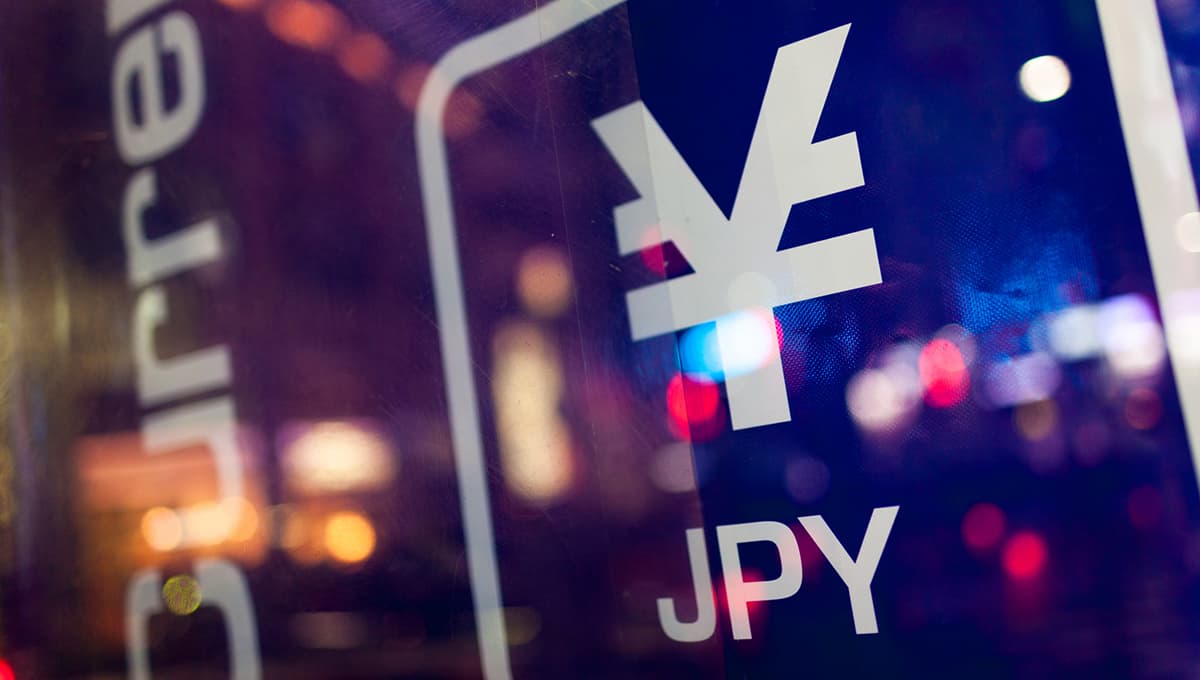 Sign of Japanese yen on a reflective background with street lights blurred in the surface