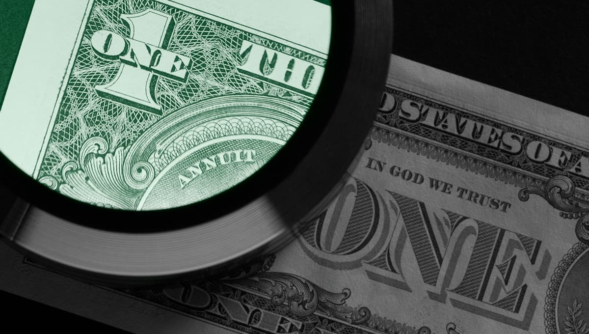 A photo of a magnifying glass examining a US dollar note