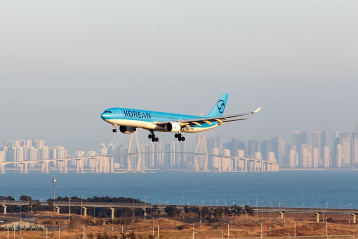 A Korean Air Airbus A330-323 aircraft, registration number HL7585, gracefully descends towards Incheon Airport, with the iconic Incheon Bridge
