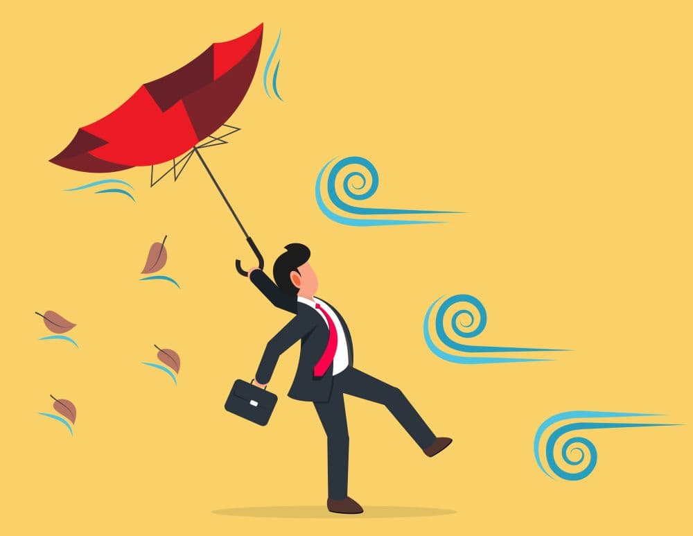 Image of businessperson struggling against wind.