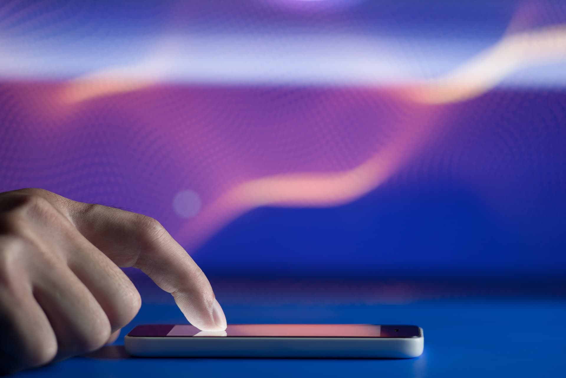 Man tapping a phone screen, set against a purple and blue background